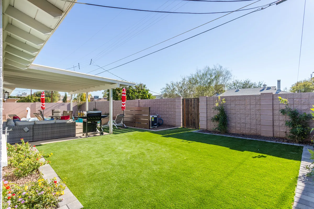 An exterior scene showcasing a cheerful patio area with ample seating, a green artificial lawn, and an outdoor grill. The setup is ideal for outdoor gatherings, barbecues, and informal meetings, capturing the essence of a relaxed yet productive retreat environment.