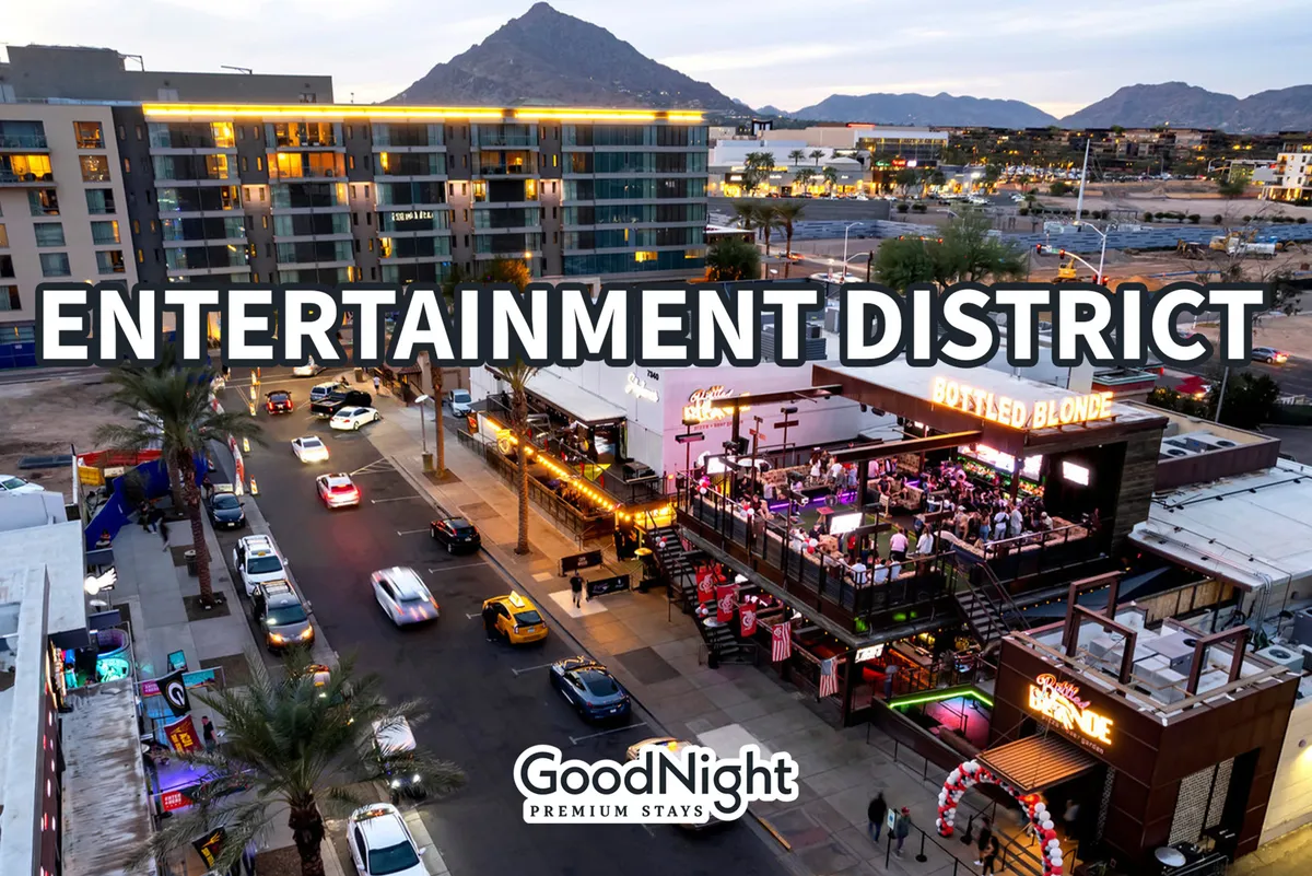 A busy street lined with entertainment venues, bustling with people against a backdrop of mountains. The scene is lively, suggesting a vibrant nightlife and a variety of places to dine, shop, and socialize.